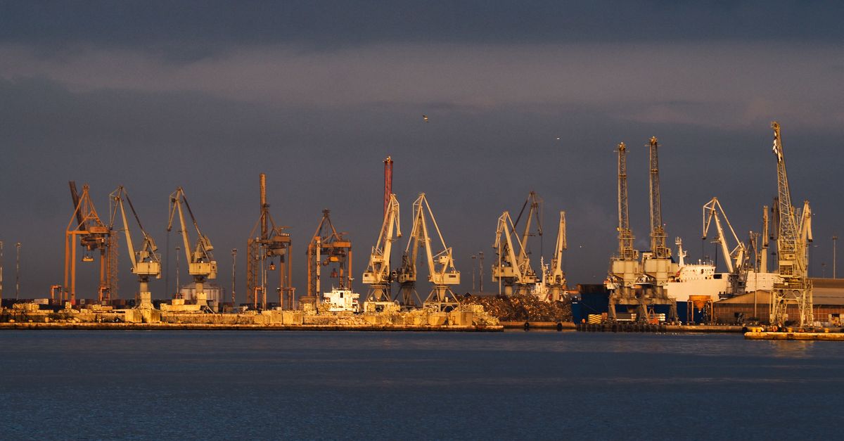 Vista de un puerto con grúas y embarcaciones al atardecer